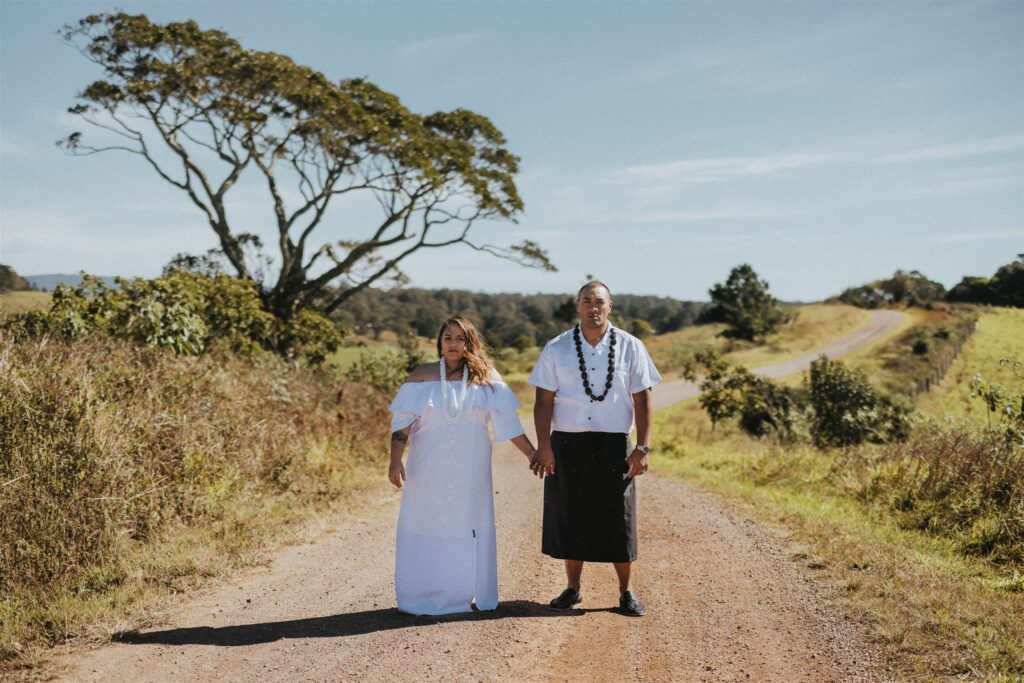 Samoan Wedding Couple wearing traditional dress and adornments staring at the camera while standing in the middle of a dirt road